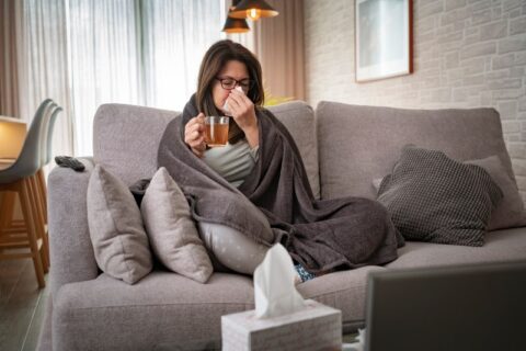 A woman sits on a gray couch before Balloon Sinuplasty treatment in Burbank, CA