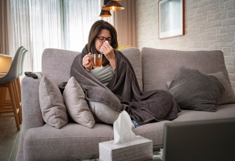 A woman sits on a gray couch before Balloon Sinuplasty treatment in Burbank, CA