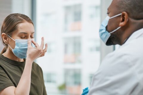 A doctor and patient, both masked, talk about sinus infections in a Burbank, CA office