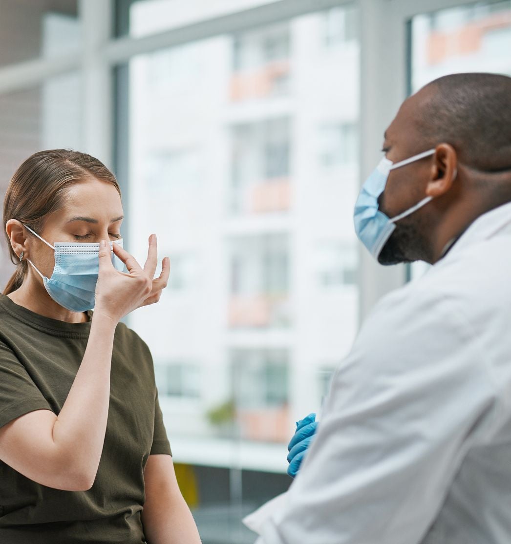 A doctor and patient, both masked, talk about sinus infections in a Burbank, CA office